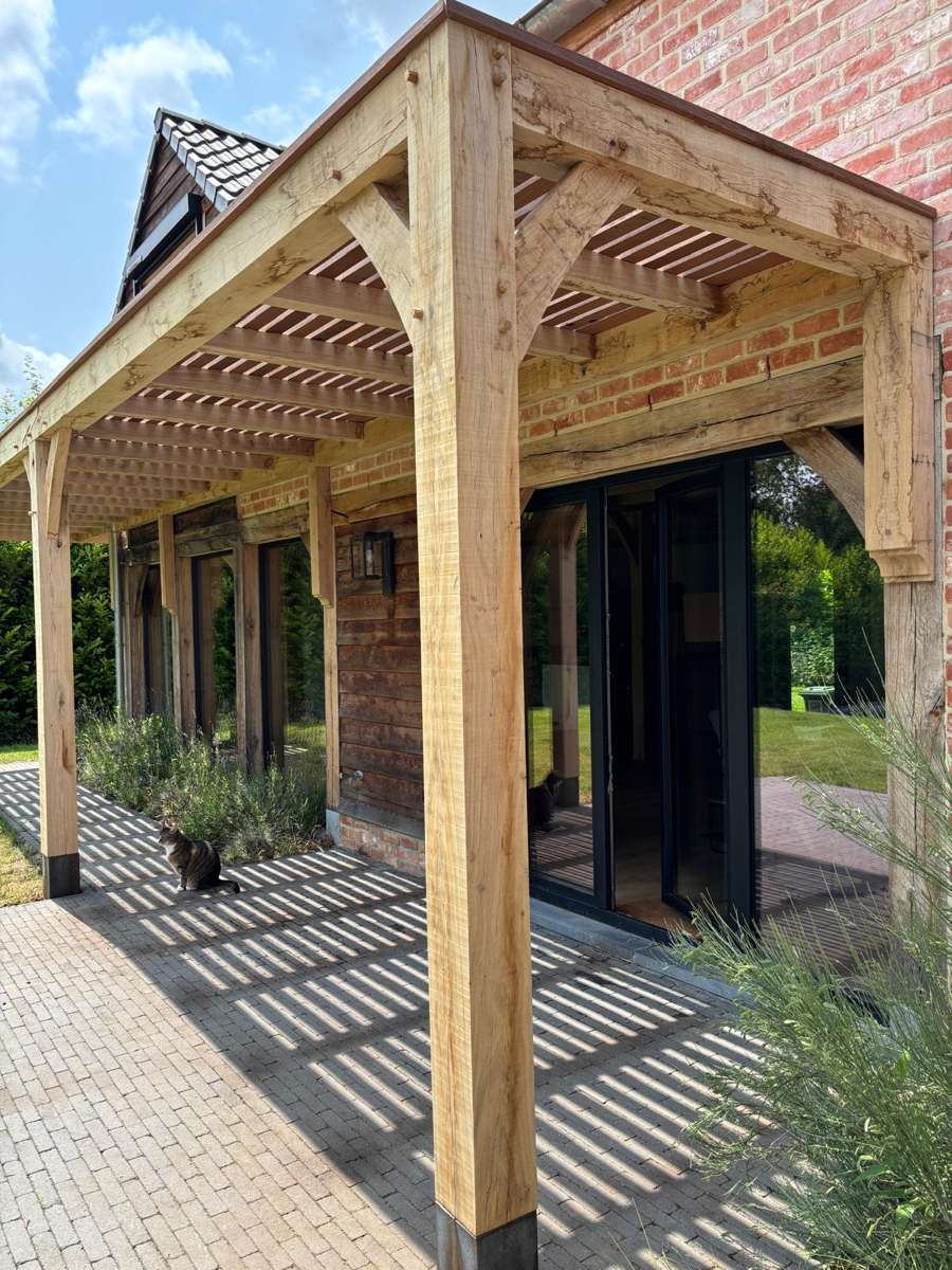 Pergola en bois livrée en kit et montée devant une maison en brique