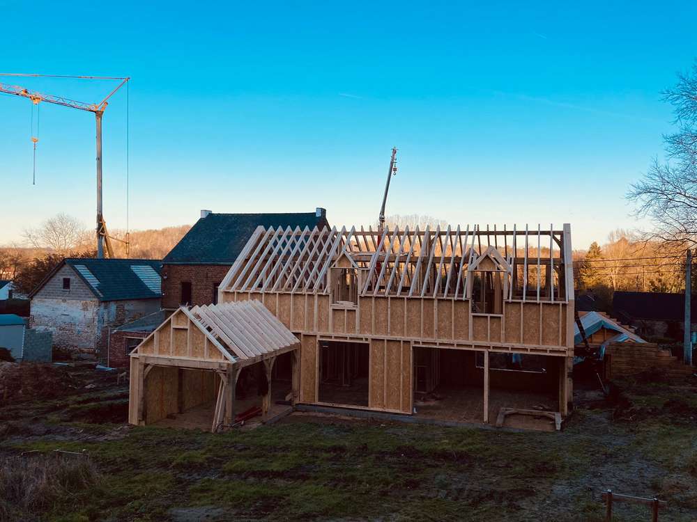 Maison à ossature et charpente de chêne au soleil couchant, grue