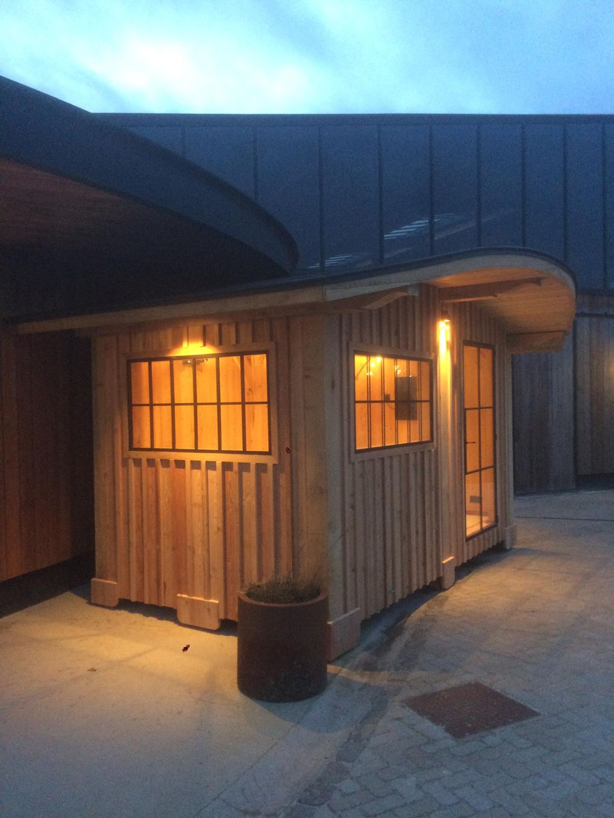 Pavillon bardage chêne vertical, toit courbe, éclairé au crépuscule