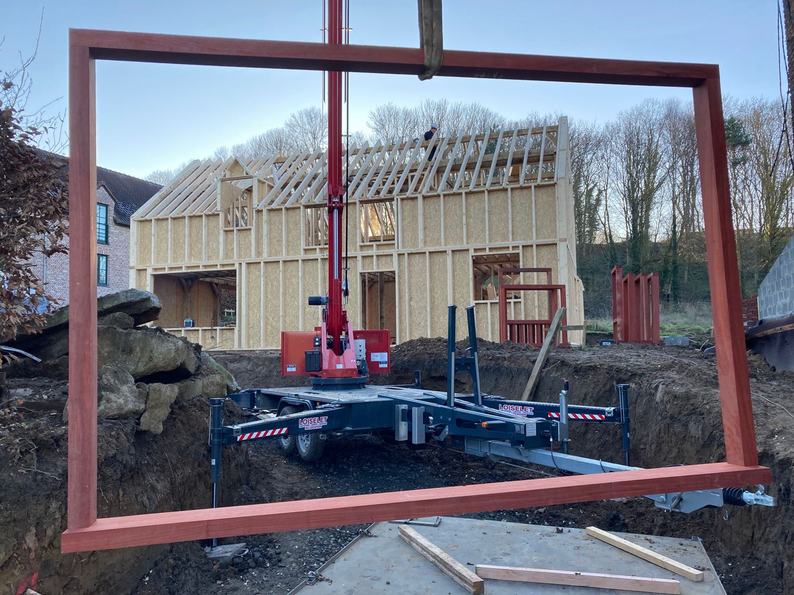 Maison ossature cadree par un chassis de fenetre suspendu a la grue