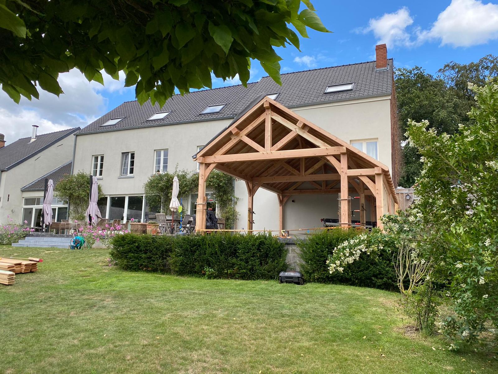 Terrasse couverte chêne terminée contre maison blanche, jardin