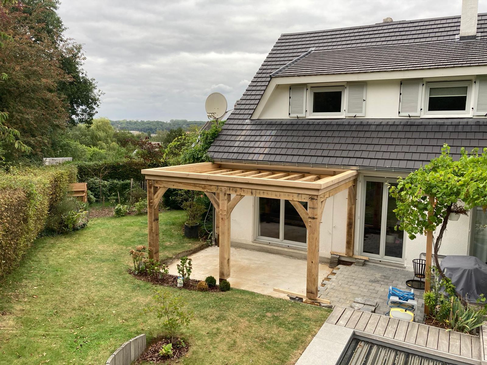 Auvent/pergola chêne contre maison blanche, jardin
